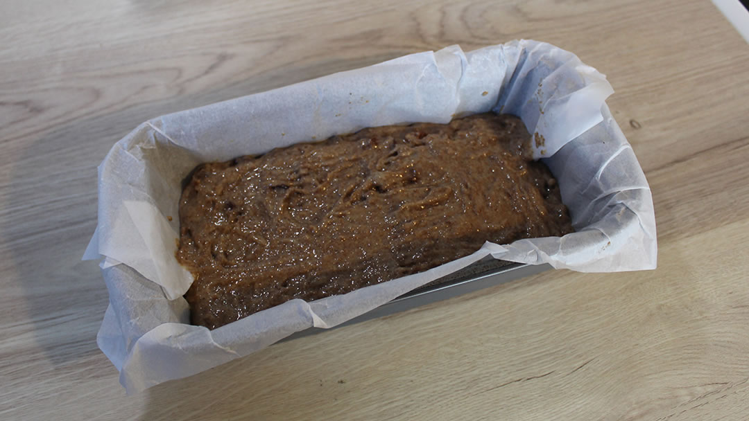 Adding the mixture to a loaf tin lined with baking paper