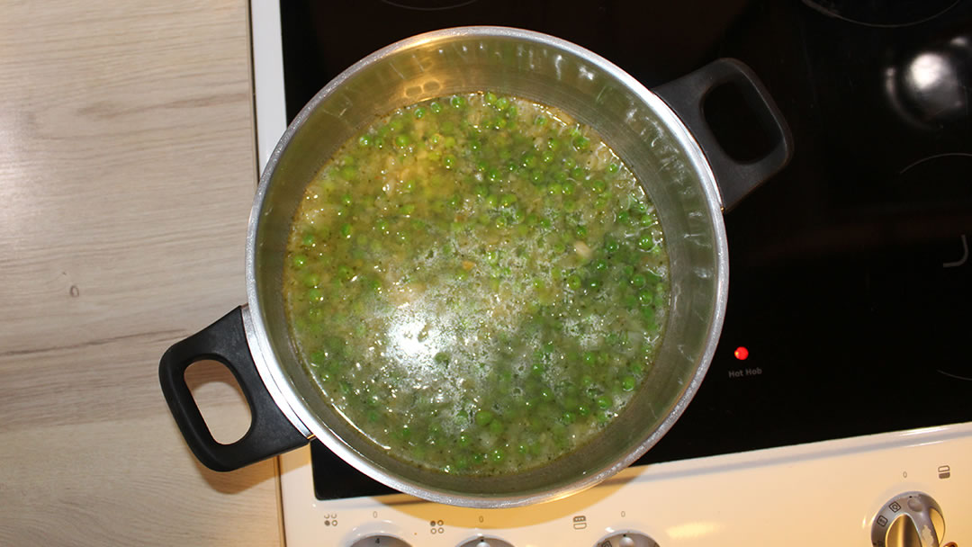 Adding the vegetable stock and frozen peas