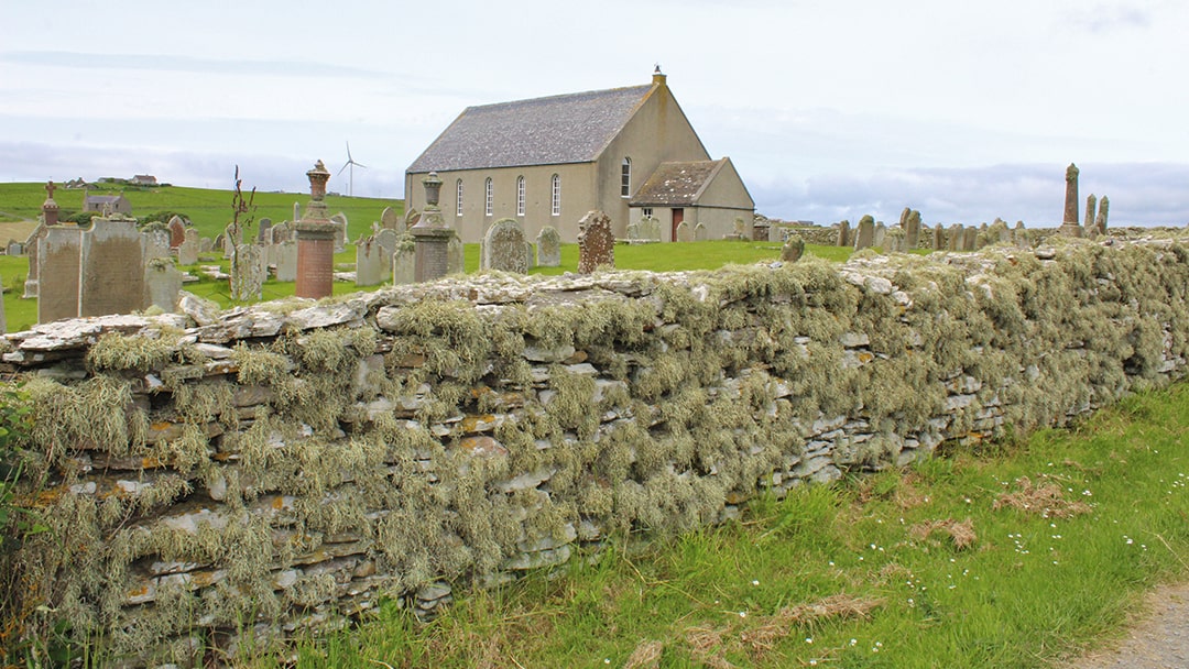 The kirk and kirkyard with its lichen-covered wall