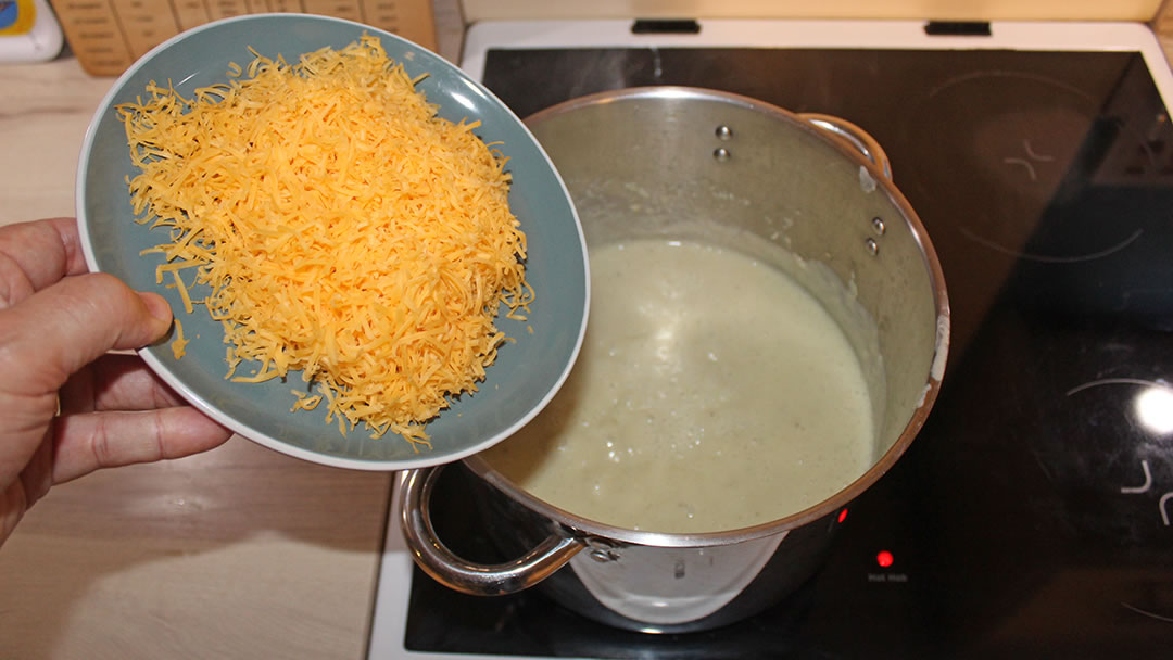 Adding the finely grated mature cheddar to the blended soup