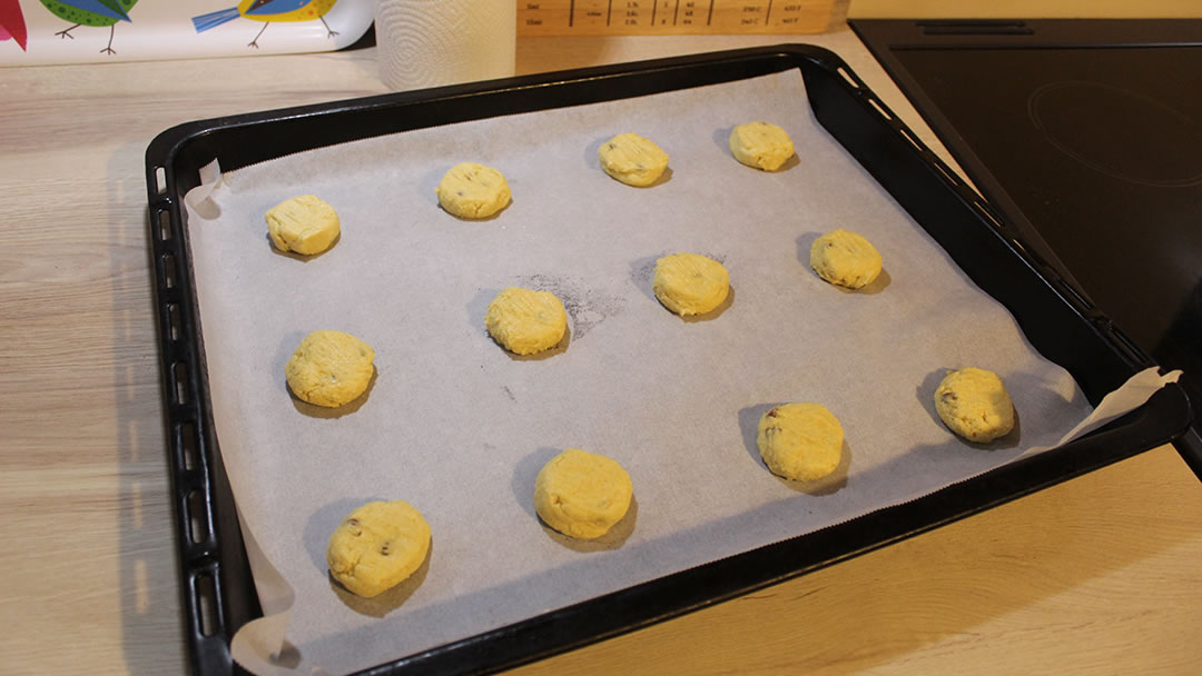 The orange biscuit mixture in flattened balls on a baking tray ready for the oven